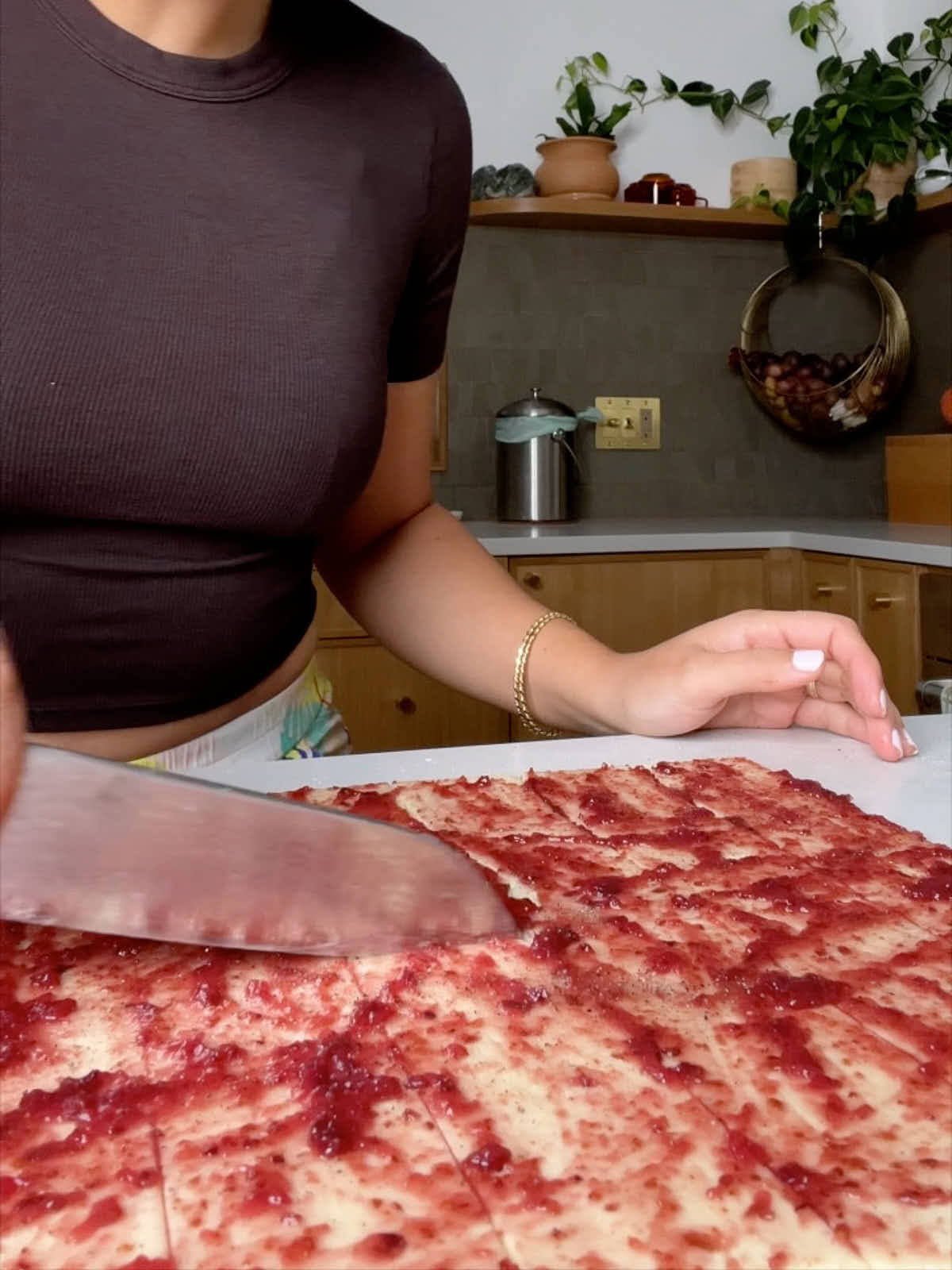 Knife cutting pastry covered in red jam.