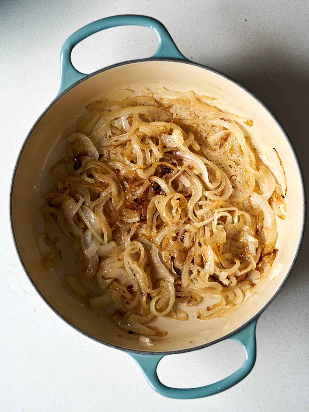 A large dutch oven with sauteed onions inside.