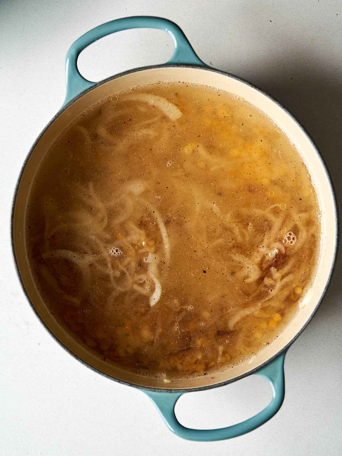 A large dutch oven with onions sauteed in broth inside.