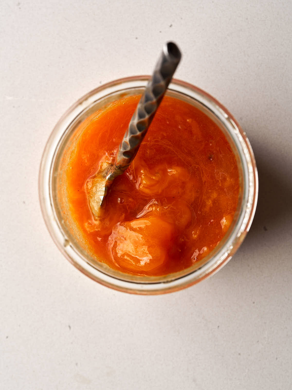 Persimmon pulp in a glass bowl with a metal spoon.