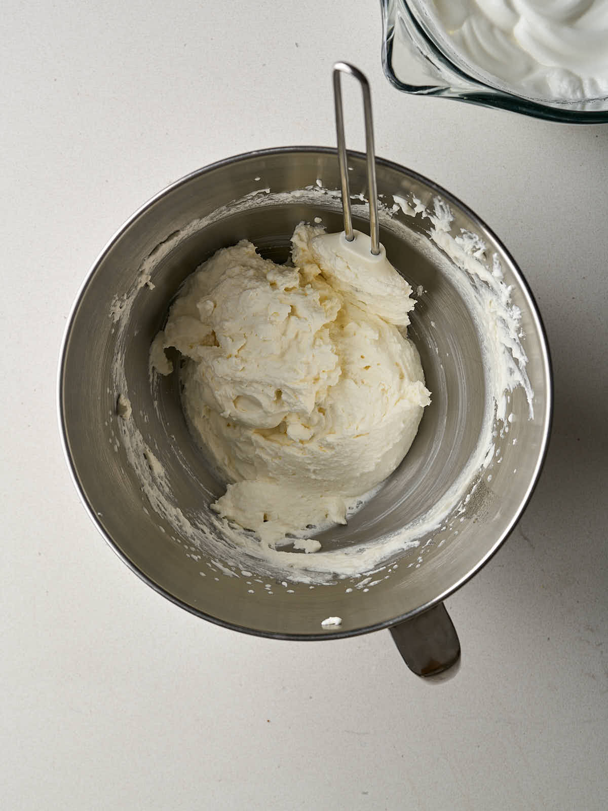 Whipped cream in the metal bowl of a stand miker.