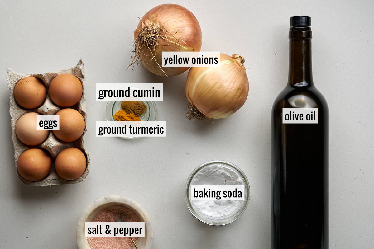 Eggs, olive oil, yellow onions, and other ingredients on a countertop.