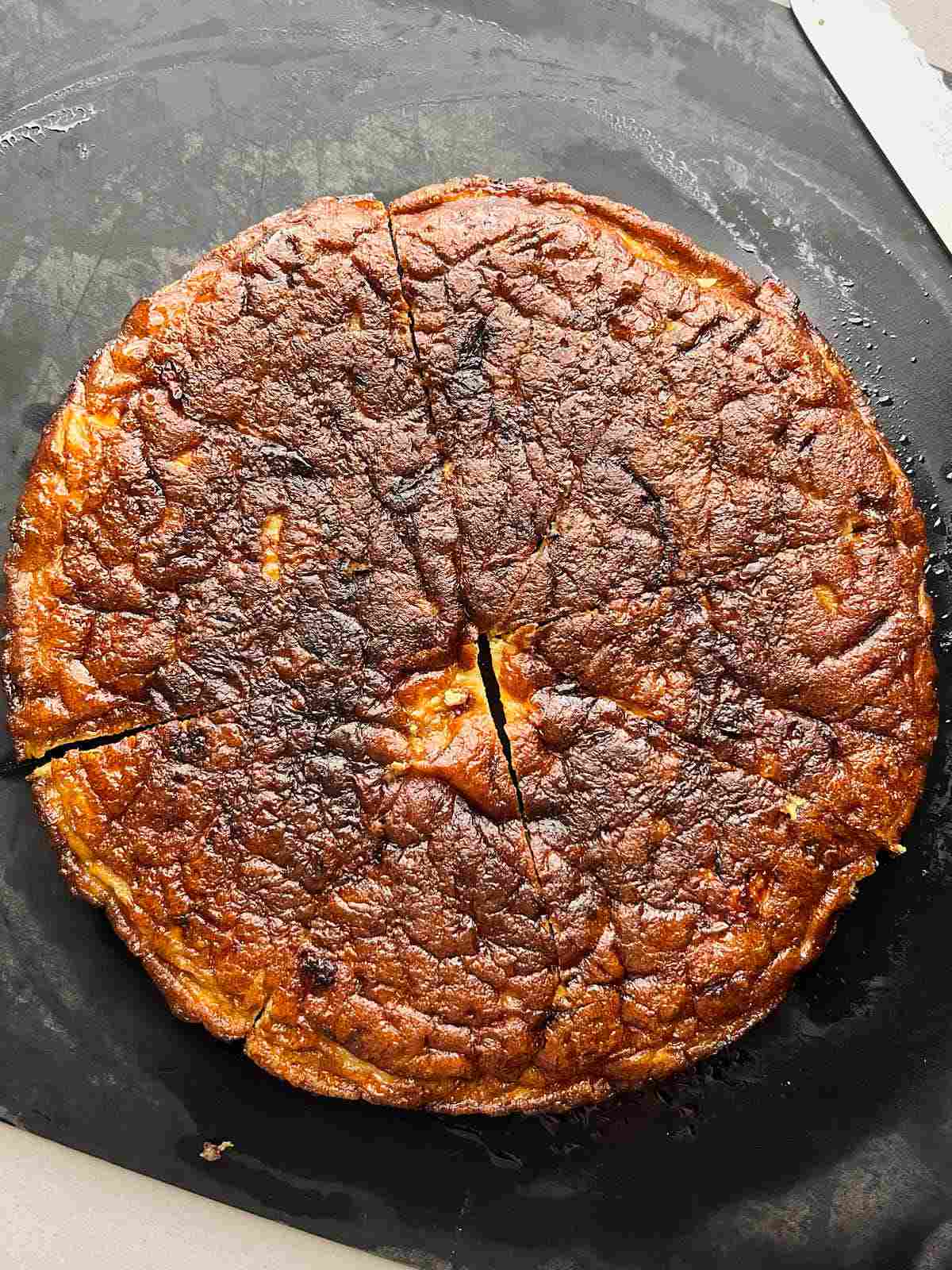 Dark browned, yellow frittata on a black cutting board.