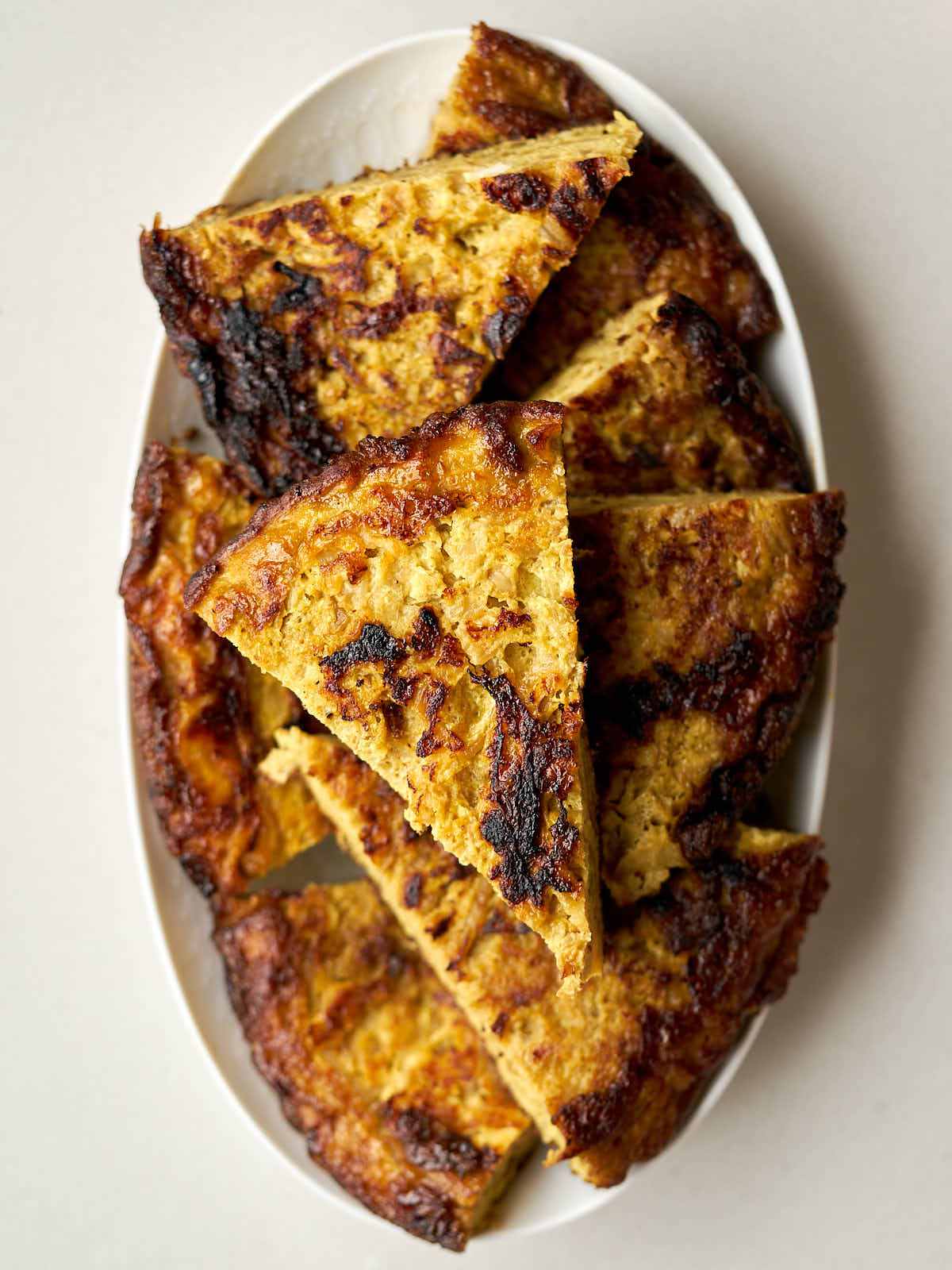 Wedges of frittata on a white, oval plate.