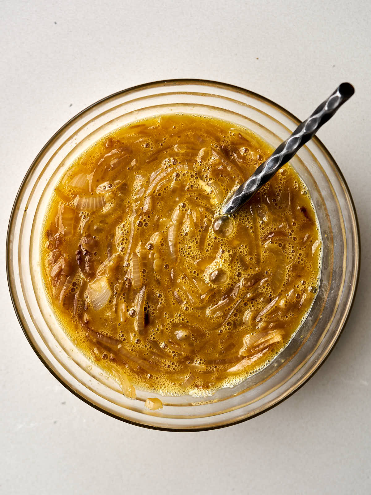 Caramelized onions scrambled into eggs in a large glass bowl.