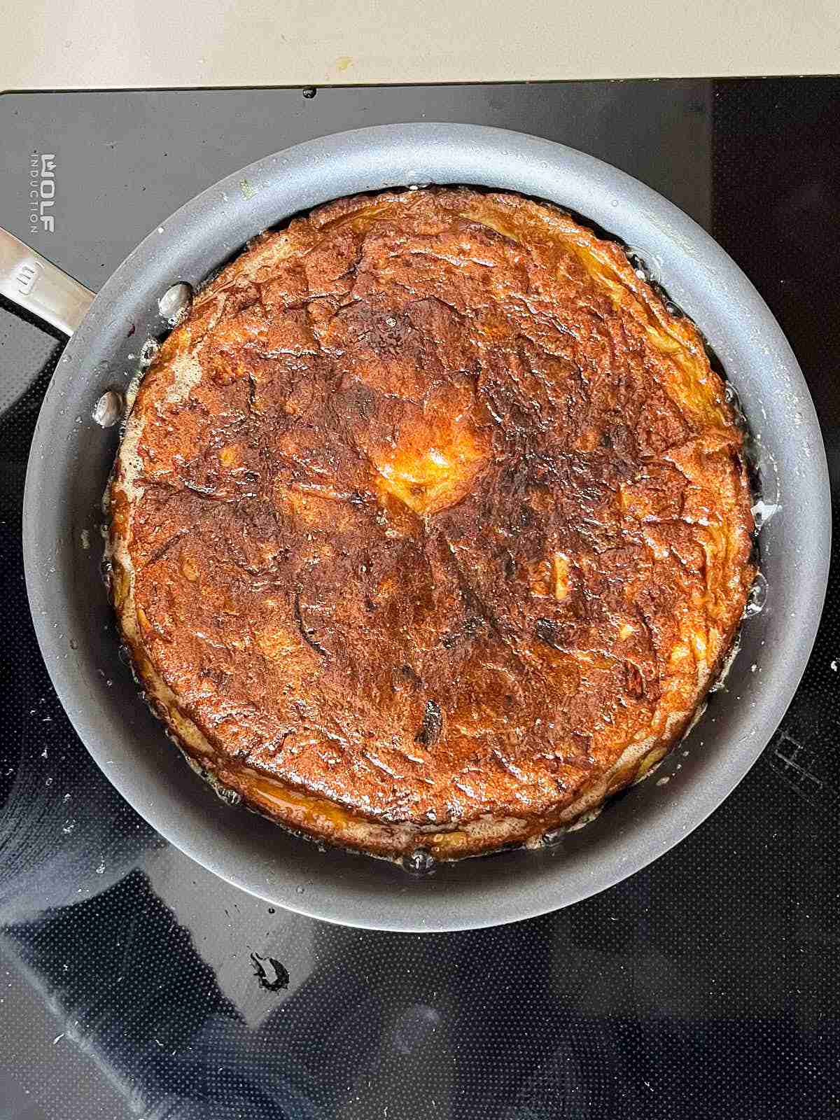 Dark browned frittata in a non-stick pan.