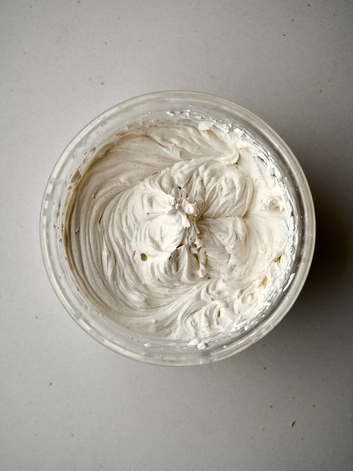 Whipped cream in a glass mixing bowl.