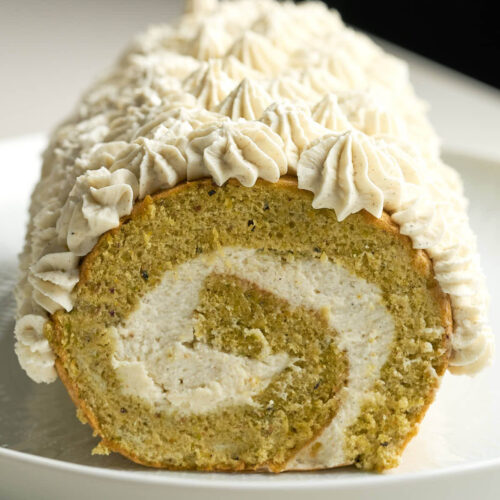 Green swiss roll cake with cream piped topping and swirl.