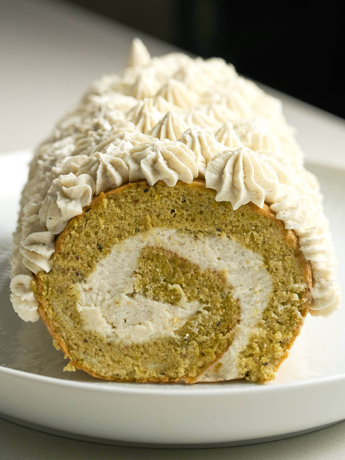 Green swiss roll cake with cream piped topping and swirl.