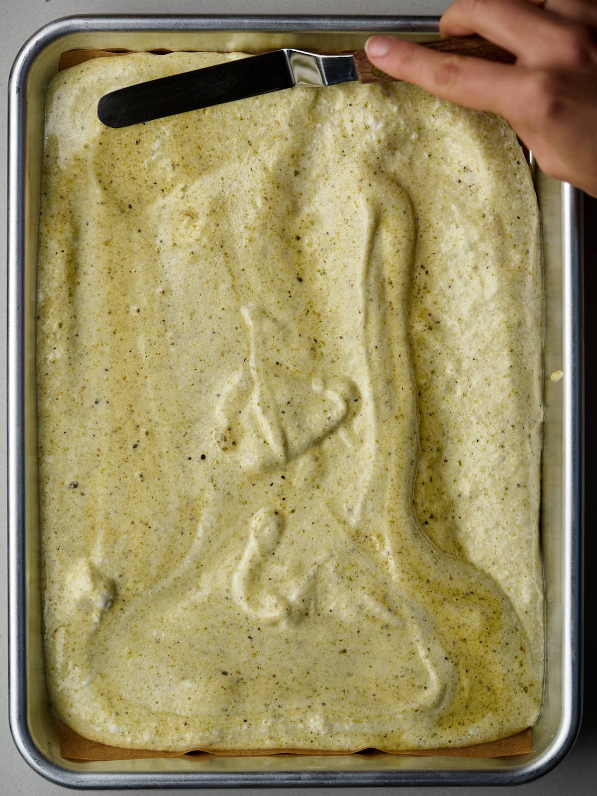 Green batter in a quarter sheet pan with a metal palette knife.