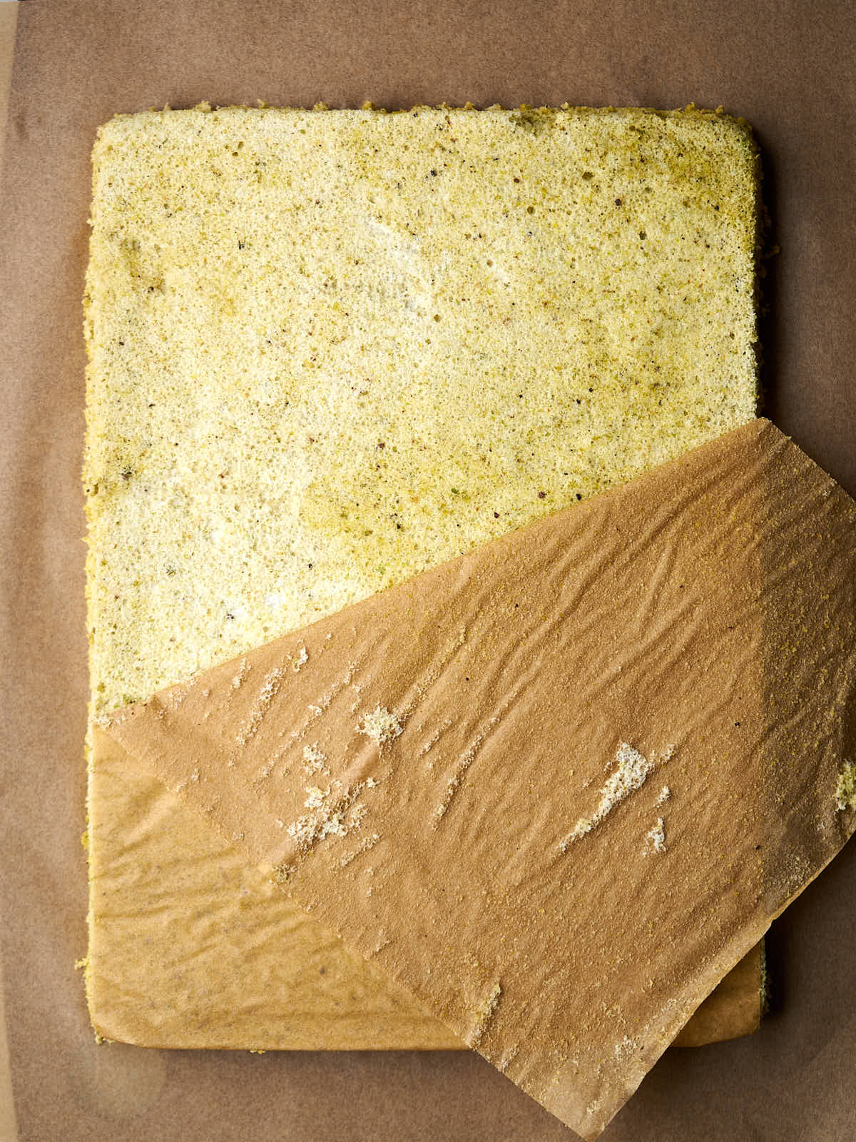 Removing parchment paper from a rectangular cake.