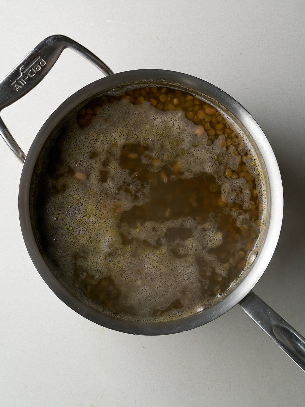 Beans cooking in water in a silver pot.