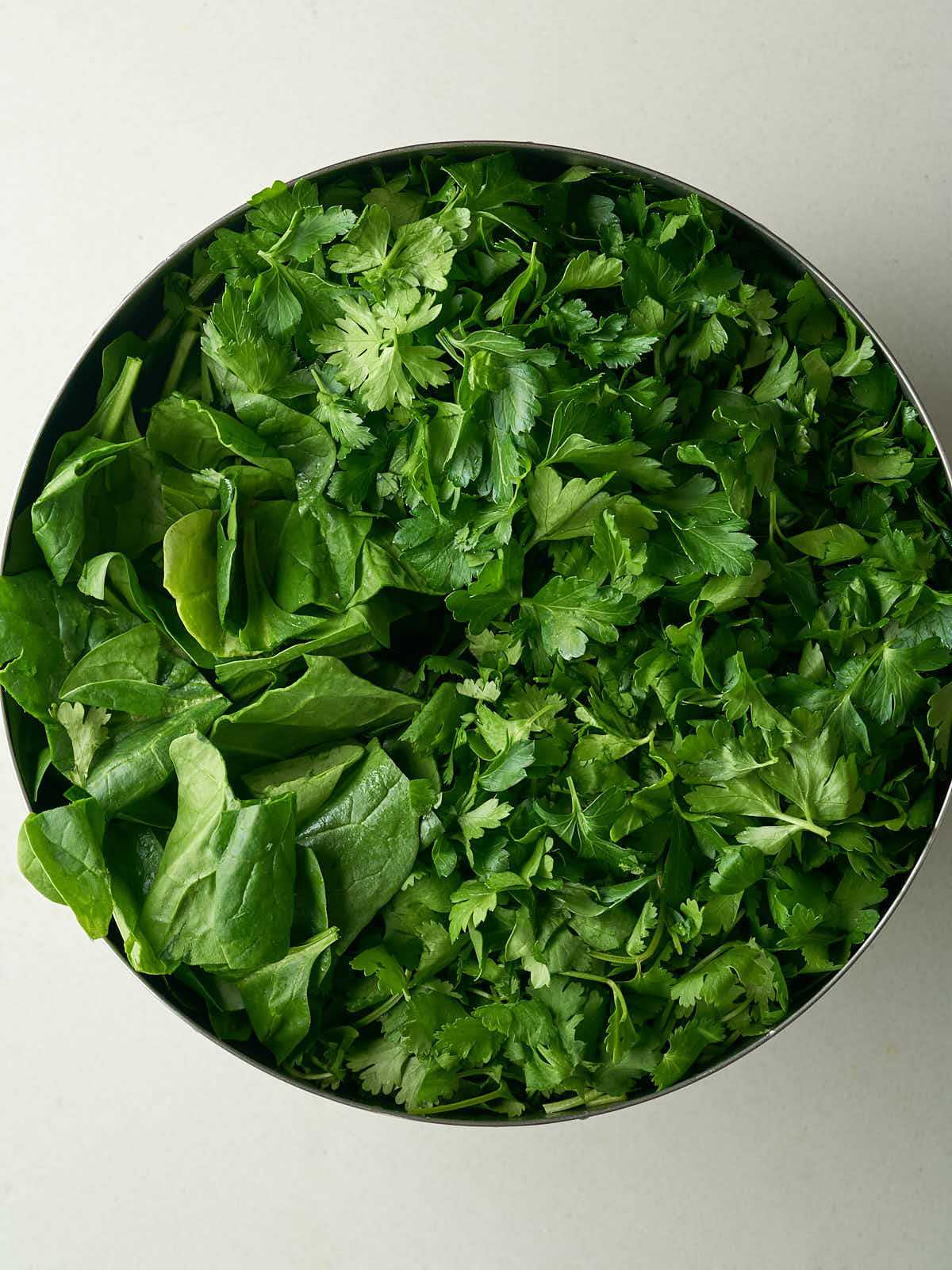 A large silver bowl filled with chopped greens.