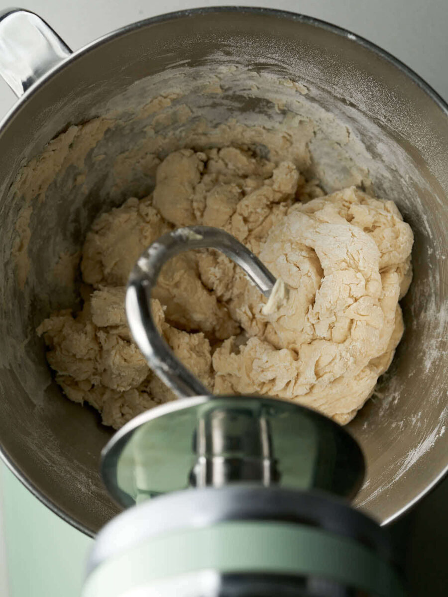 Dough in the metal bowl of a mint green stand mixer.