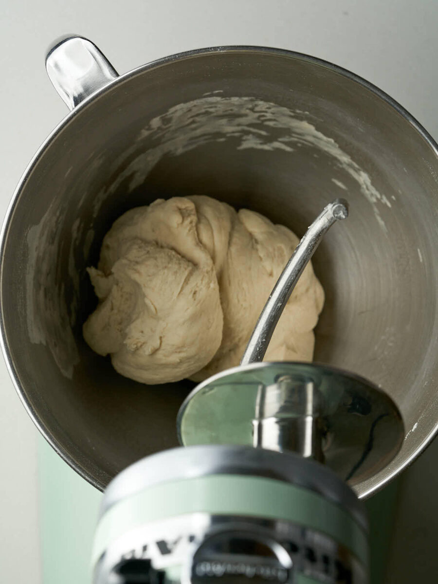 Kneaded dough in the metal bowl of mint green stand mixer.