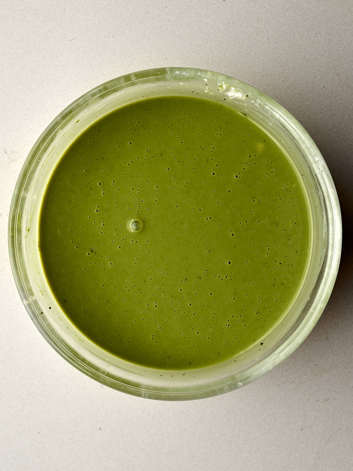 Thick green liquid with small bubbles in a glass bowl.