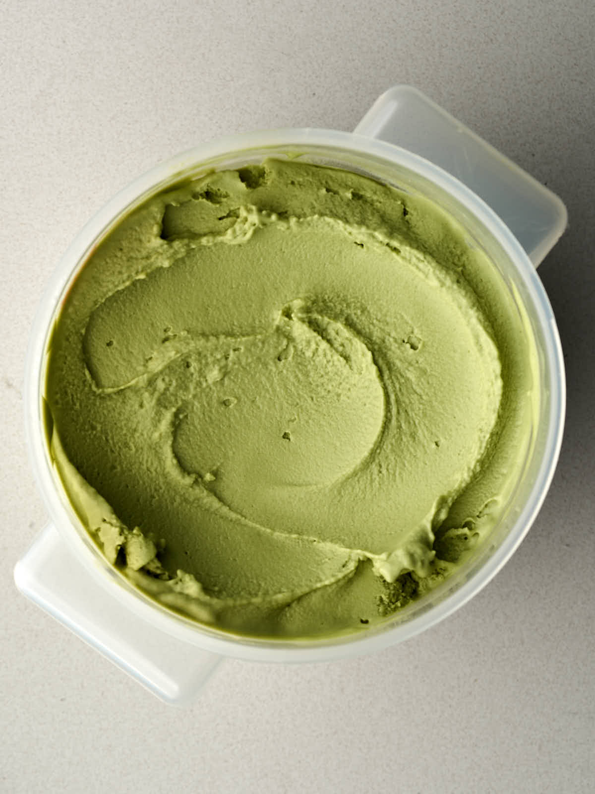 Green ice cream in a plastic Cambro bin.