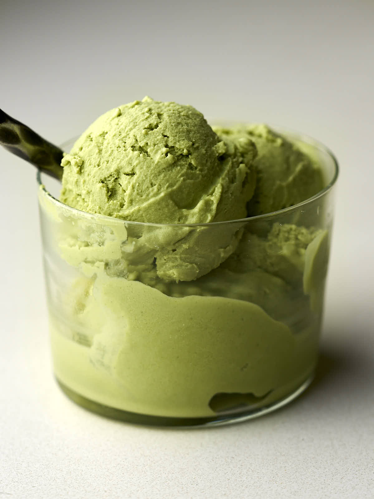 Green ice cream in a small glass with a metal spoon.