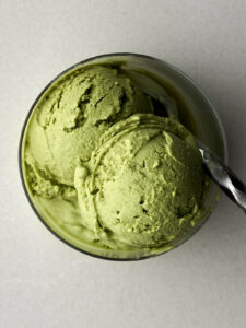 Green ice cream in a small glass with a metal spoon.