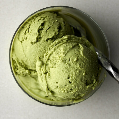 Green ice cream in a small glass with a metal spoon.