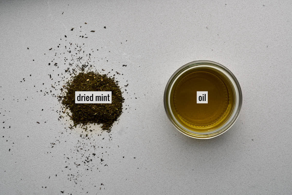 A small bowl of oil next to a pile of dried mint.