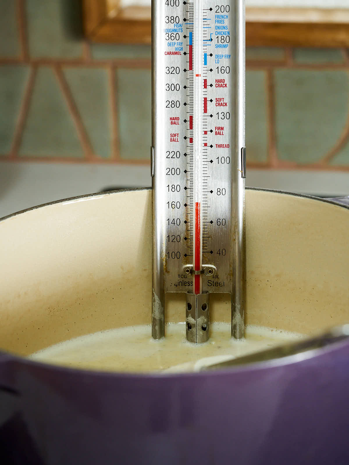 Candy thermometer in a purple cast iron pot.