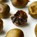 Dried limes on a countertop with the one in the middle cut open so you can see the dark brown flesh inside.