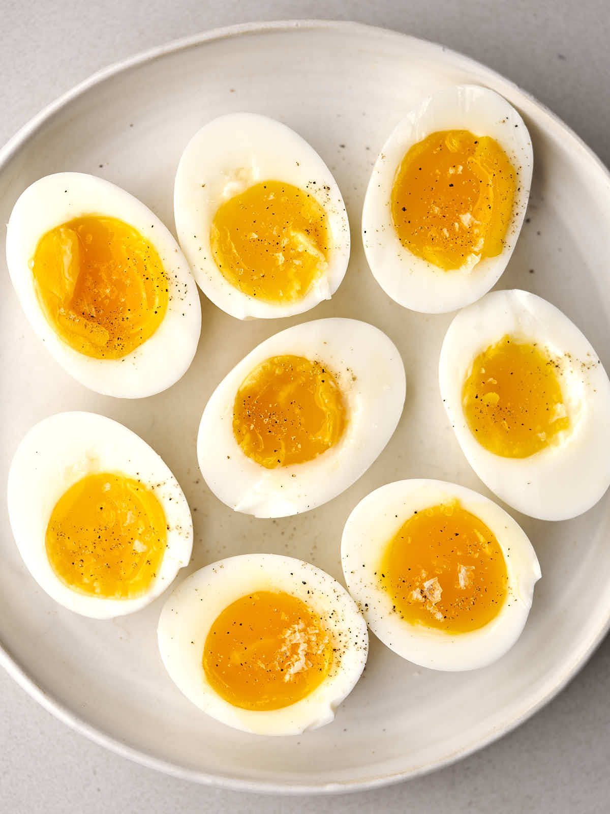 Eight jammy egg halves on a white plate.