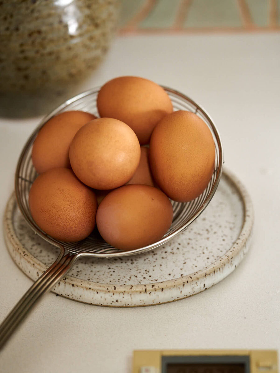 Brown eggs on a metal slotted spoon resting on a spoon rest.