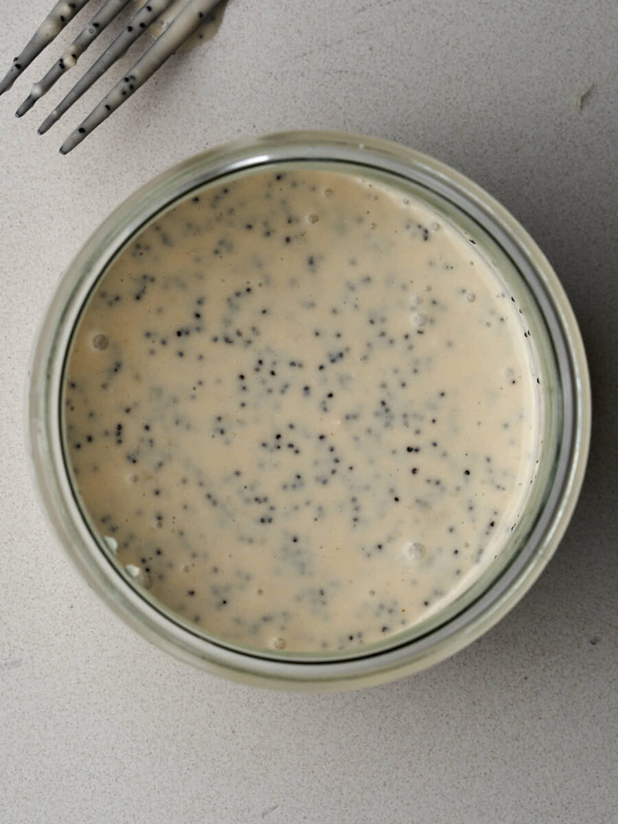 Poppyseed dressing in a jar next to a fork.