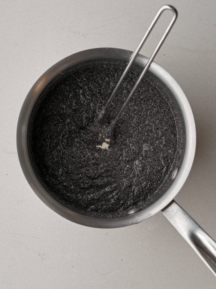 Poppyseeds in a metal saucepan with a rubber spatula.